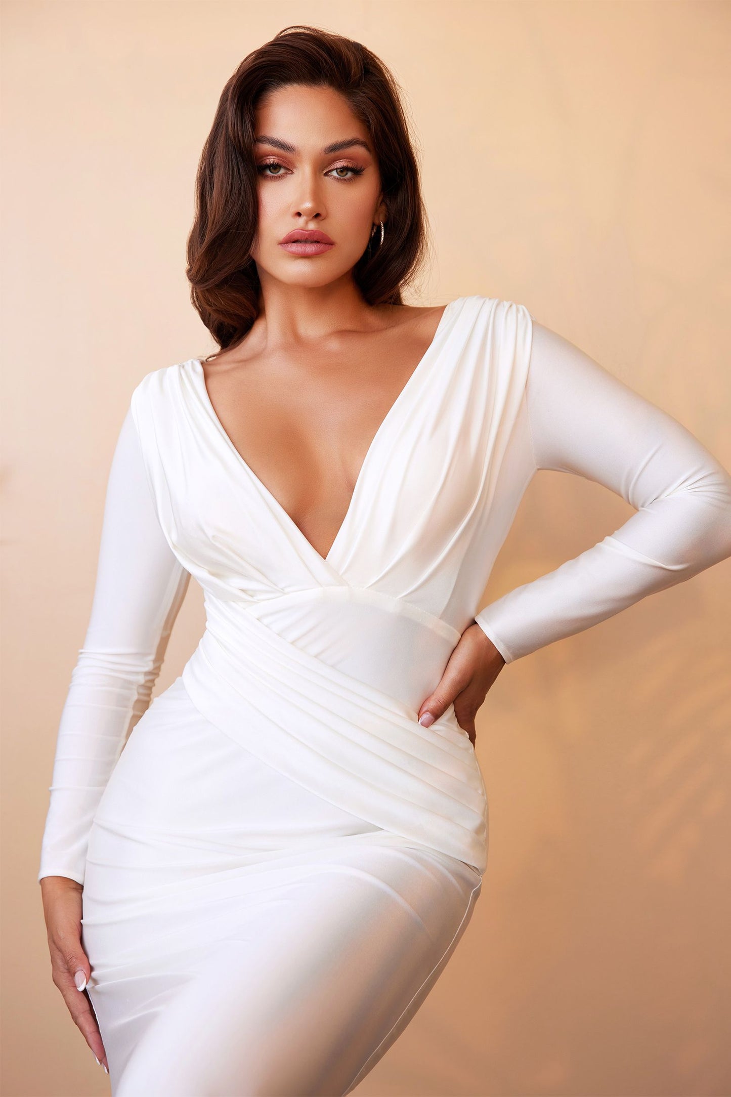 Elegante vestido de novia manga larga con delicados botones cubiertos recorren el centro de la espalda y un escote pronunciado sobrepelliz y un panel plisado asimétrico en forma de fajín cubre la cintura