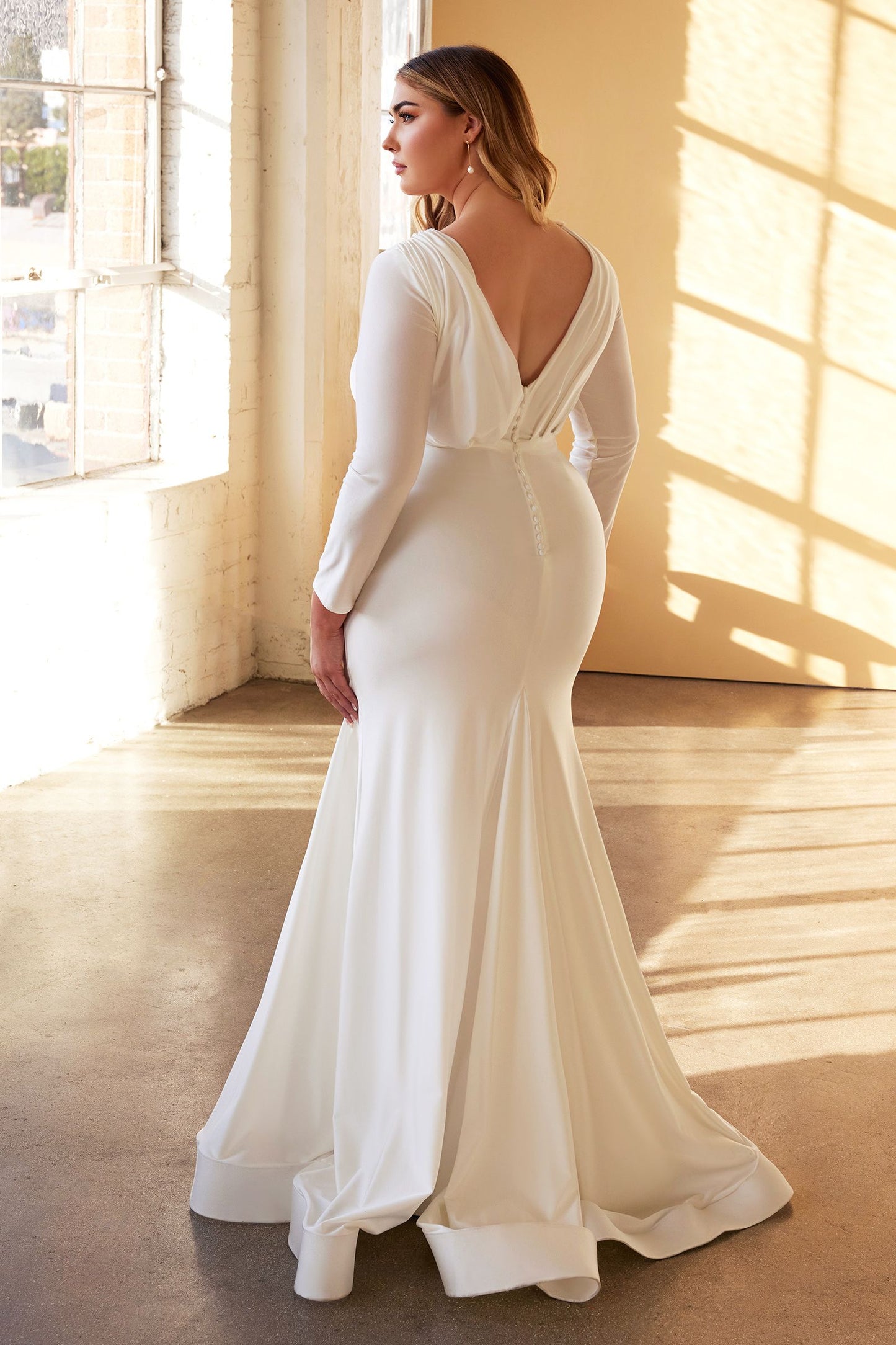 Elegante vestido de novia manga larga con delicados botones cubiertos recorren el centro de la espalda y un escote pronunciado sobrepelliz y un panel plisado asimétrico en forma de fajín cubre la cintura