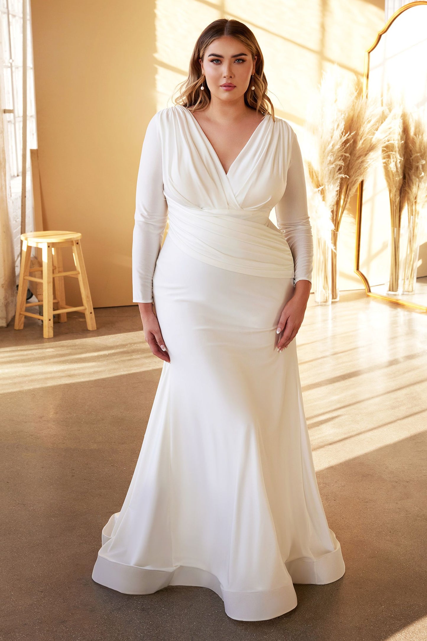 Elegante vestido de novia manga larga con delicados botones cubiertos recorren el centro de la espalda y un escote pronunciado sobrepelliz y un panel plisado asimétrico en forma de fajín cubre la cintura