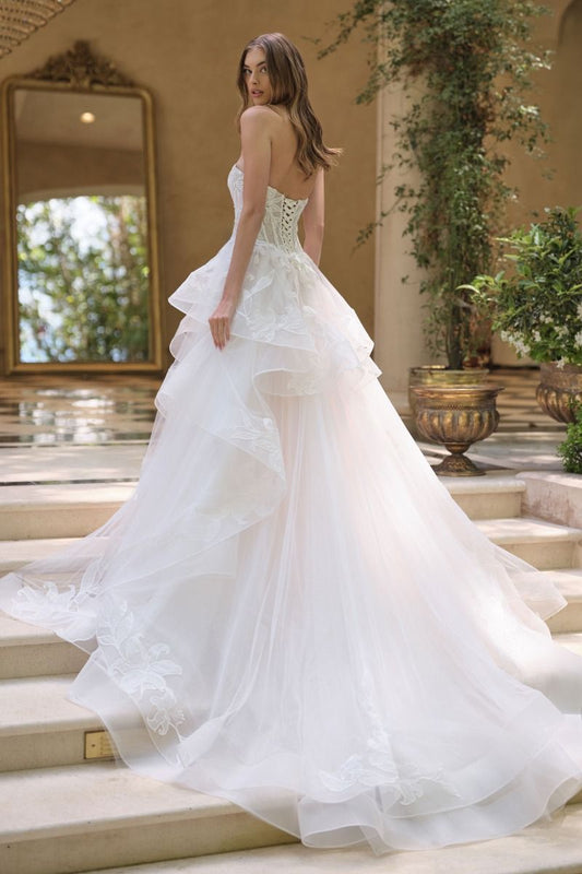 Vestido de novia que presenta un escote corazón sin tirantes y un corpiño semitransparente con varillas y una falda de tul escalonada en cascada está adornada con un delicado diseño floral de lirios estrellados